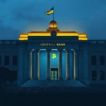Budynek banku centralnego w nocy, z podświetlonym logo Bitcoina na elewacji i flagą z symbolem Bitcoina na dachu.